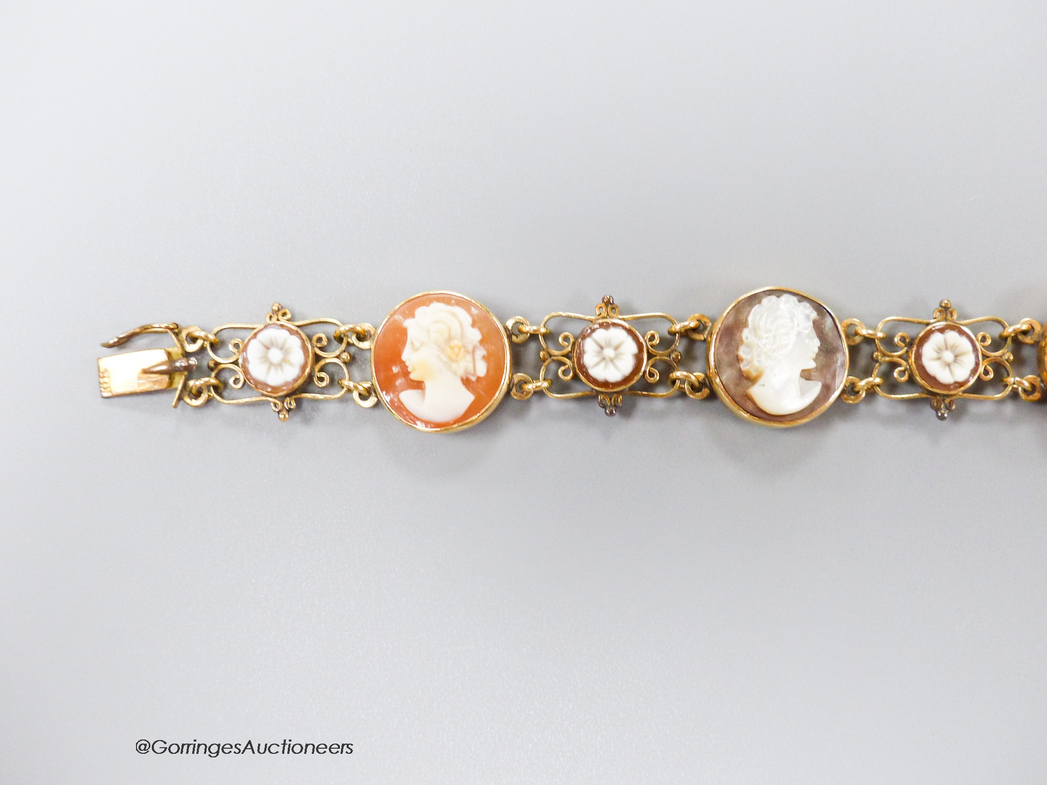 A 14k yellow metal, multi carved cameo and flowerhead set bracelet, including paua shell, shell and coral, carved with the busts of ladies, to dexter and sinister, 16.5cm, gross weight 13.5 grams.